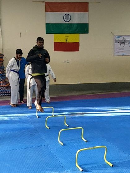 A coach demonstrates proper form while jumping over hurdles. Our instructors lead by example, participating in the drills alongside the students.
