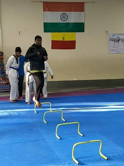 An athlete airborne over agility hurdles. This kind of plyometric training builds explosive power for kicks and footwork.