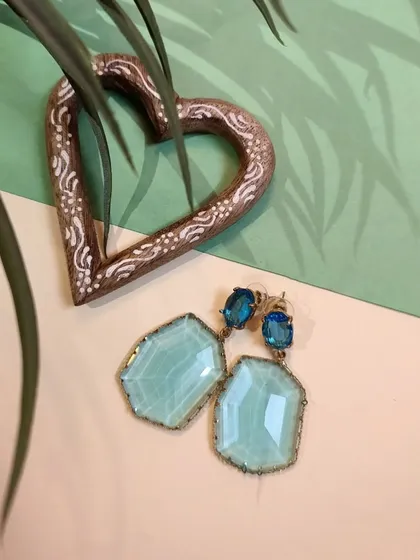 A styled shot of the aqua blue crystal earrings with a heart decor piece, perfect for a gift.