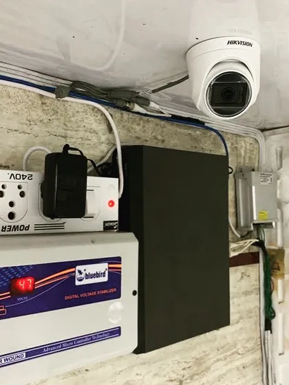 A complete professional setup with a Hikvision dome camera connected to a DVR, power strip, and a digital voltage stabilizer for protection against power fluctuations.