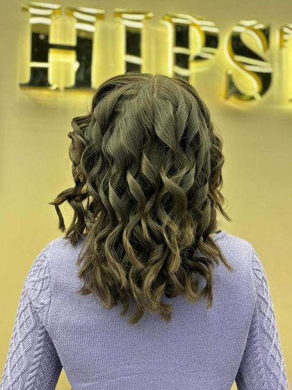 The back of a young client's hair, showing the beautiful, uniform curls created by our stylists.