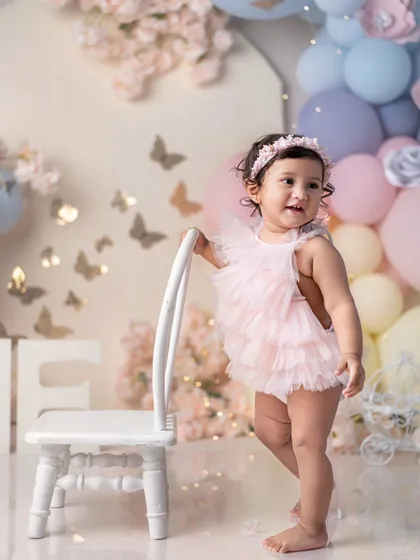 A princess in her pink tutu, standing by a tiny chair. She looks so proud to be one!