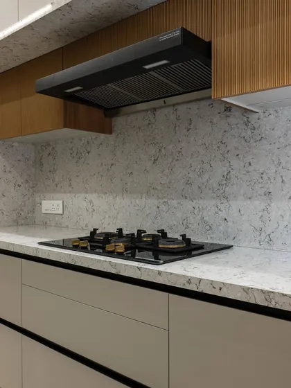 The combination of fluted wood upper cabinets and a speckled quartz countertop adds subtle texture and visual interest to this otherwise minimalist design. The under-cabinet lighting provides warm, functional task lighting.