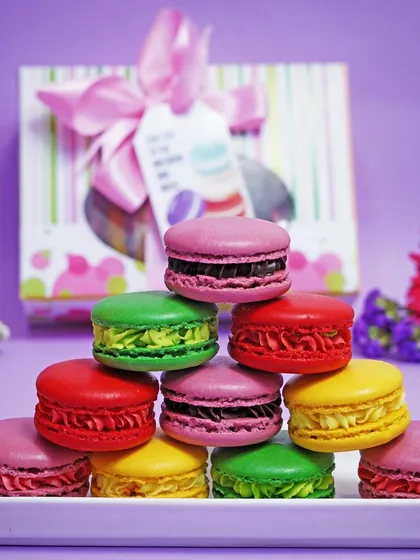 A playful pyramid stack of assorted macarons, with a gift box in the background. This creative composition is eye-catching and perfect for social media marketing.