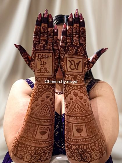 A bride showing off her full-arm henna stain. The deep, dark color makes the personalized text and intricate patterns stand out beautifully.