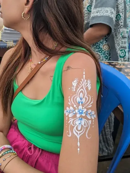 This is an example of my white henna-style body art. The intricate floral and scrollwork design is painted by hand, offering a stunning and elegant look for weddings, sangeets, or festivals.