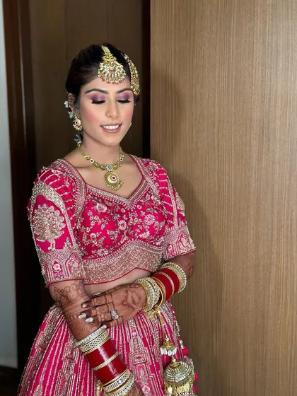 A beautiful portrait of bride Ashmeet. The soft pink makeup tones harmonize perfectly with her bright pink lehenga and gold jewelry.