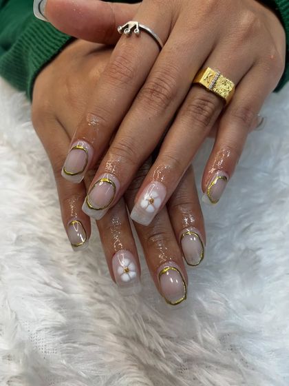 A close-up of the gold chrome frame and 3D flower nail art. This design is done on soft gel extensions, which provide the perfect canvas for such detailed work.