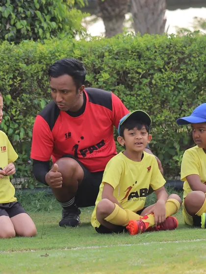 We specialize in nurturing young talent by providing everything they need to thrive. This photo shows a coach giving personalized attention, a cornerstone of our holistic approach.