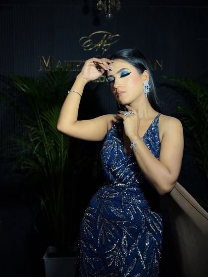 A confident pose showcasing the blue smokey eye. The dark, moody lighting adds to the drama of the look.