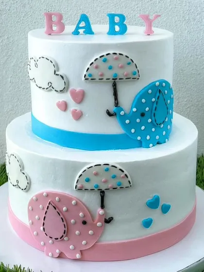 This adorable two-tier baby shower cake features cute pink and blue elephants under umbrellas. It's a sweet way to celebrate a new arrival.