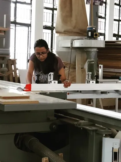 A student uses the sliding table on a panel saw to safely and accurately cut a large sheet of material to size.