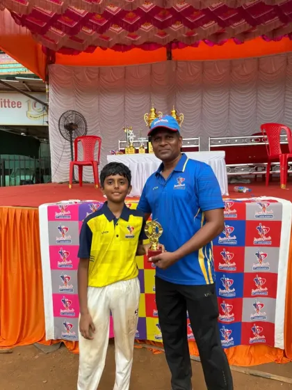 An award winner from the U-10 tournament stands proudly with his coach and trophy after the final match.