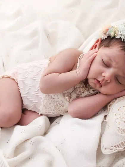 A little angel, dreaming sweetly. This newborn portrait with a delicate floral crown and soft, lacey outfit is all about capturing innocence. The simple, clean background keeps all the focus on your baby's serene beauty.