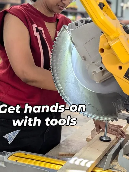 Get hands-on with tools. A member carefully lines up a piece of wood for a precise cut on the DeWalt mitre saw, a key piece of equipment in our woodworking zone that's available for all members to use.