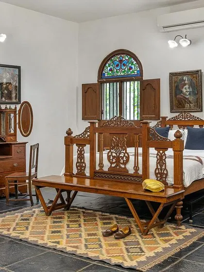 A wider view of the Vasishta suite, showcasing the spacious layout, antique vanity, and beautiful stained-glass windows that let in dappled light.