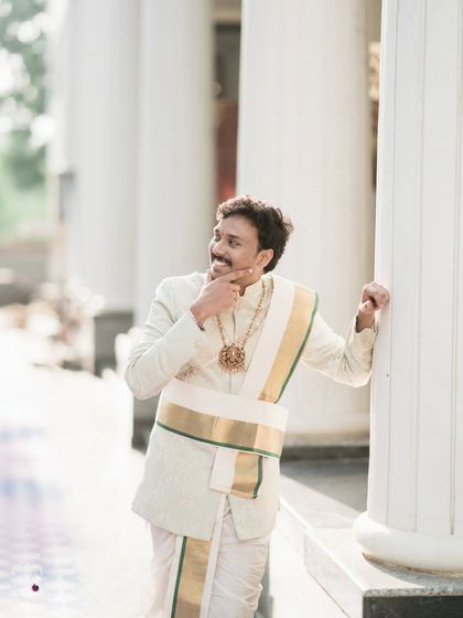 A royal portrait of the groom in his traditional white and gold wedding attire.
