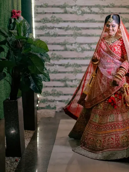 A full-length shot of the bride, her red veil flowing behind her. This image captures the grandeur and grace of the bridal look.