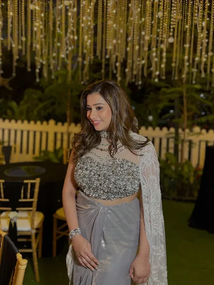 For this engagement party, we went for sheer elegance. The look features glowing, glass-like skin and soft smoky eyes, paired with a modern draped saree and voluminous waves for a super glam finish.