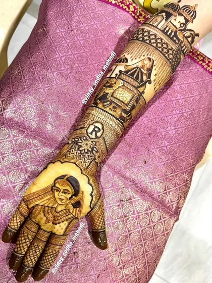 A personalized bridal design featuring a portrait of the bride on the palm, her initial 'R' on the wrist, and a doli scene on the forearm. Every detail is crafted to tell her story.