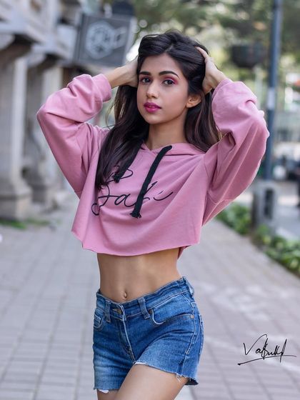 A close-up street fashion portrait that highlights the model's expression and attitude. The hands-in-hair pose adds a touch of playful energy to this stylish urban shot.