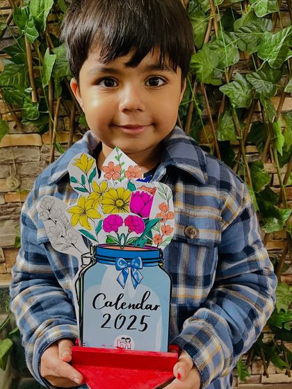 A proud student holding the 2025 calendar he finished in our New Year's workshop.