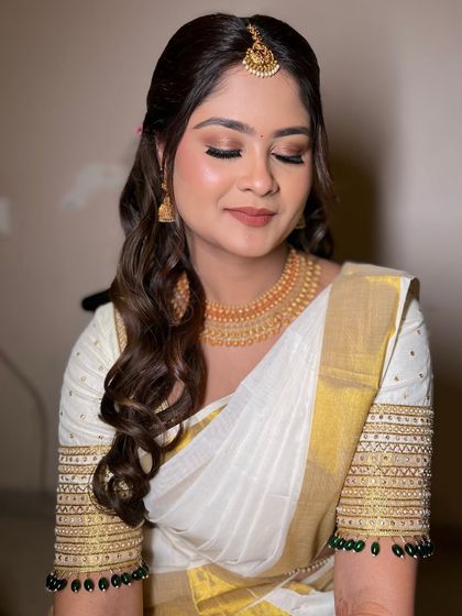 Soft South Indian bridal elegance. This look features soft, closed eyes to showcase the warm, neutral eyeshadow that complements her traditional white and gold saree.
