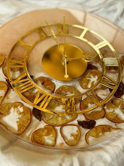 A unique wall clock made with preserved orange slices and strawberry chunks. This fun and fruity clock is a perfect way to add a pop of color and personality to your kitchen or dining room.