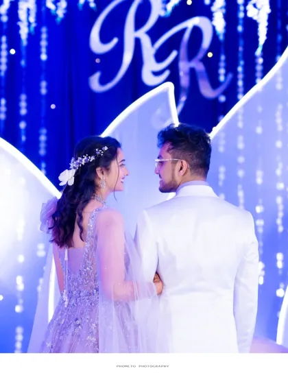 A beautiful shot from behind, capturing the couple looking out at their reception, with their monogram glowing in the background.