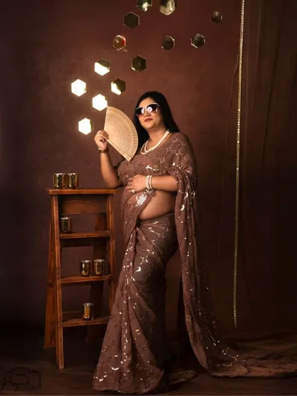 A fun and sassy pose with a fan and sunglasses. This shows that maternity shoots can be playful and full of personality!