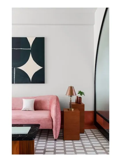 A vignette from the family lounge, showing the interplay of color, form, and material. The custom pink sofa, geometric floor, and dark wood side tables create a composition of smaller, interesting spatial moments.