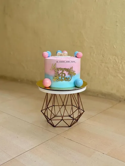 A sweet pink and blue "Mommy to be" cake decorated with colorful balls. A lovely centerpiece for a baby shower.
