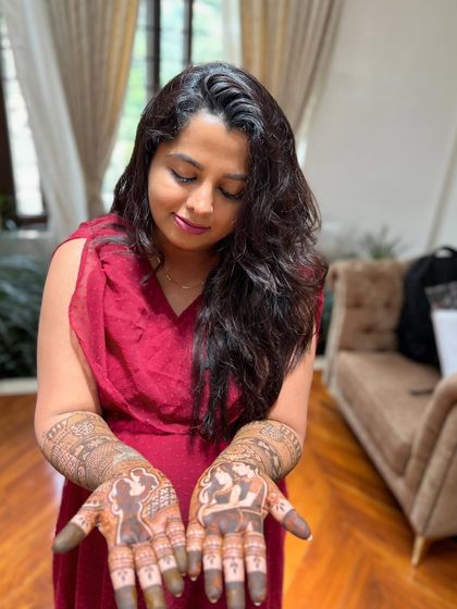 A happy mom-to-be showing off her personalized henna. The design on her palms features portraits that tell her unique story as she prepares to welcome her little one.
