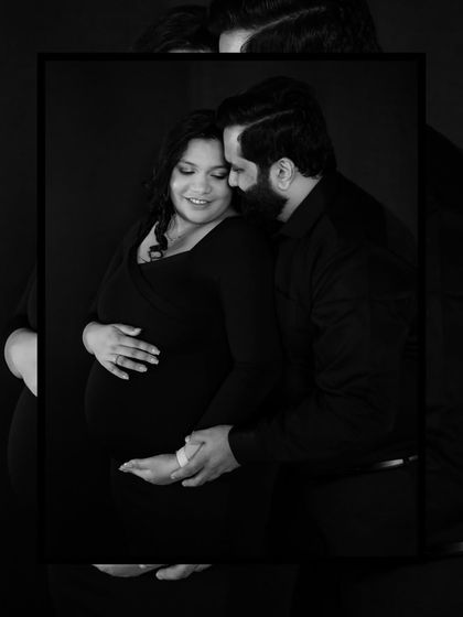 A moody and intimate black and white portrait, focusing on the quiet strength and love shared between the parents-to-be.