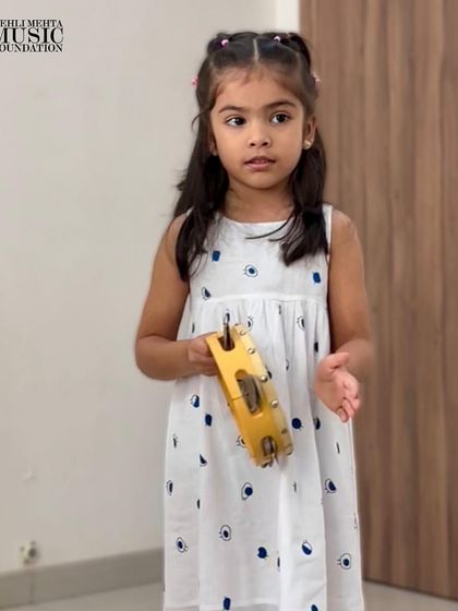 A young musician explores the sound of a tambourine. We provide a variety of age-appropriate instruments for children to experiment with during our classes.