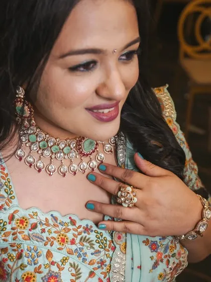 This bride looks fresh and lovely in a floral print lehenga. She chose a kundan necklace with mint green and ruby accents, along with a statement ring, to complement her colorful outfit.