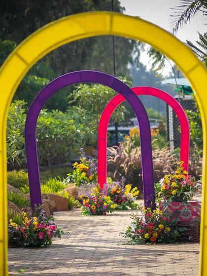 Colorful arches creating a tunnel-like entrance through the venue's garden path for the Haldi ceremony.