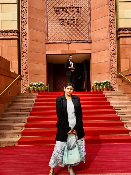 Posing on the red-carpeted steps of the Parliament building, this shot captures the grandeur of the location and the elegance of the outfit.