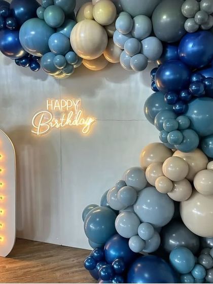 A detail shot focusing on the texture and color combination of the balloon arch and the warm glow of the "Happy Birthday" neon sign, key elements of the stylish 50th birthday setup.