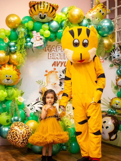 The birthday girl and her tiger friend posing for a picture in front of the jungle-themed backdrop.