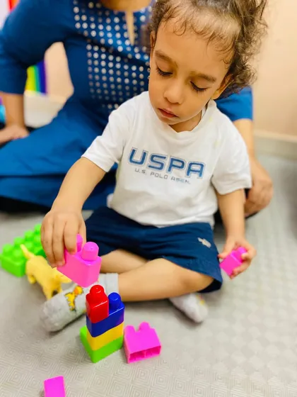 Building towers and imagination! A child is engaged in block play, a fundamental activity for developing spatial reasoning and fine motor skills, with his parent right there to support and encourage him.