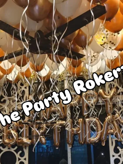 A closer look at the ceiling balloon decoration, showing the mix of chrome and latex balloons with hanging ribbons for a full and festive effect.