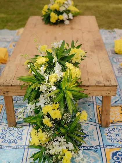 I created this relaxed, low-seating area for guests with a rustic wooden table, yellow cushions, and a beautiful floral runner, all set on a traditional blue and yellow patterned mat.