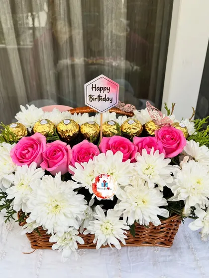 A classic and elegant birthday gift. This beautiful wicker basket is filled with fresh pink roses, white chrysanthemums, and delicious Ferrero Rocher chocolates, topped with a "Happy Birthday" sign.