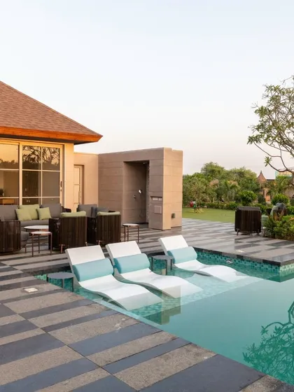 A luxurious poolside area with in-water lounge chairs and comfortable outdoor seating. The design focuses on creating a resort-like feel, blending relaxation with sophisticated style.