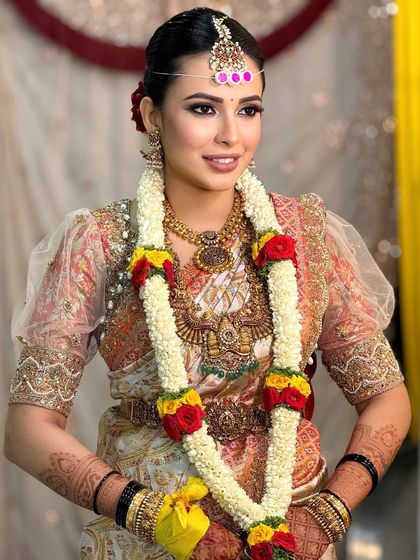 The bride during her ceremony, adorned with a beautiful flower garland. The makeup is designed to stay perfect throughout the rituals.