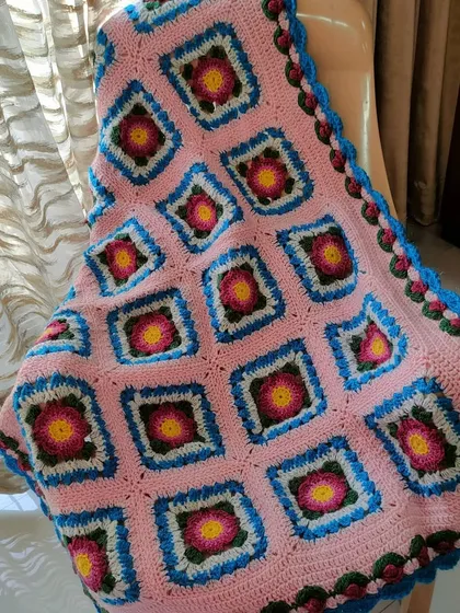 Draped over a chair, you can see how the Lydia blanket adds a touch of handmade charm and color to a room.