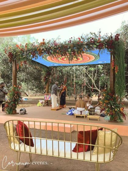 The mandap for a backyard wedding, featuring a custom mandala ceiling and rustic floral decor, perfectly framed by the surrounding trees.