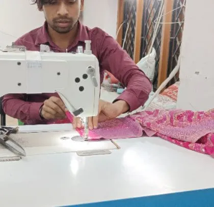 Another of my expert tailors is seen here working on a vibrant pink garment with detailed embroidery. Each member of my team is a specialist, bringing years of experience to every piece they help create.