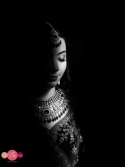 A low-key black and white portrait of the bride, where light carves out her features and jewelry against a dark background.